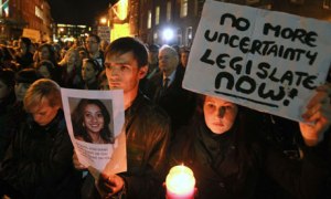 protesters hold pictures of woman who died after beng refused a termiation